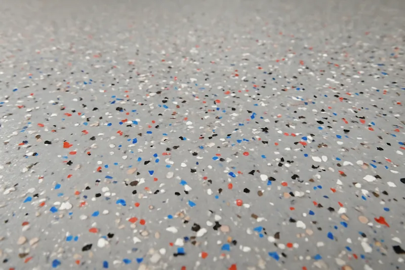 A close-up of a floor with scattered multi-coloured flakes in a clear coat — decorative flake floors, Bendigo. Illustrative example.