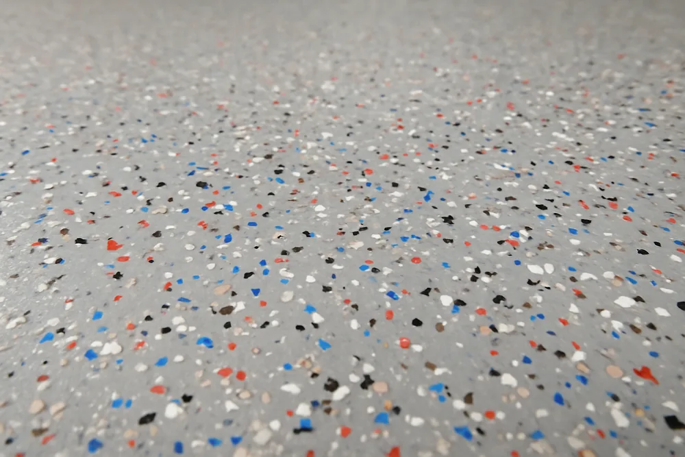A close-up of a floor with scattered multi-coloured flakes in a clear coat — decorative flake floors, Bendigo. Illustrative example.